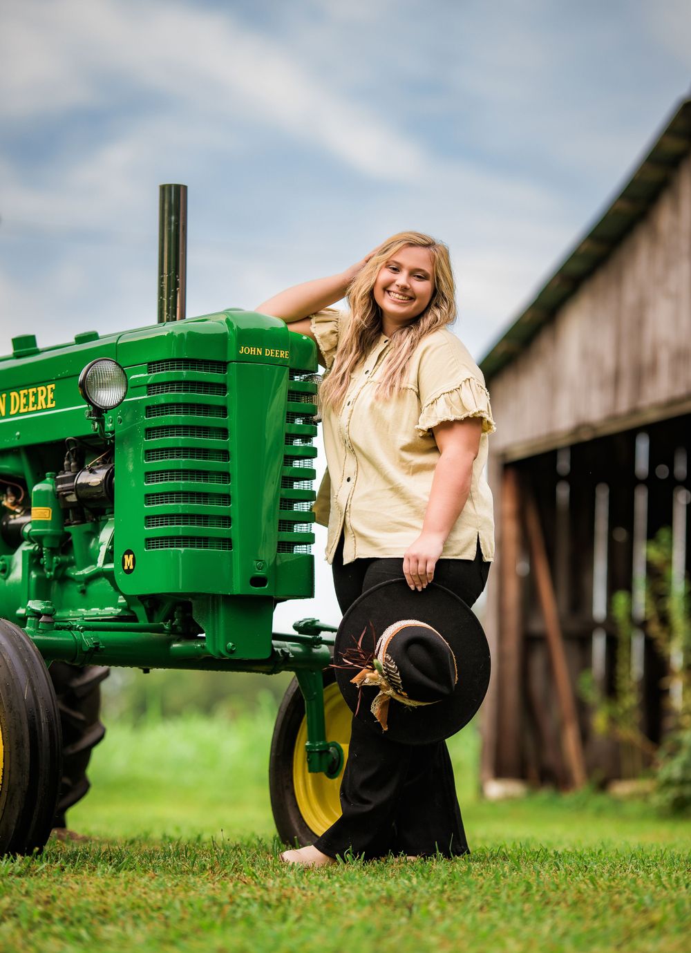 Country themed portrait with classic green John Deere tractor and barn backdrop.