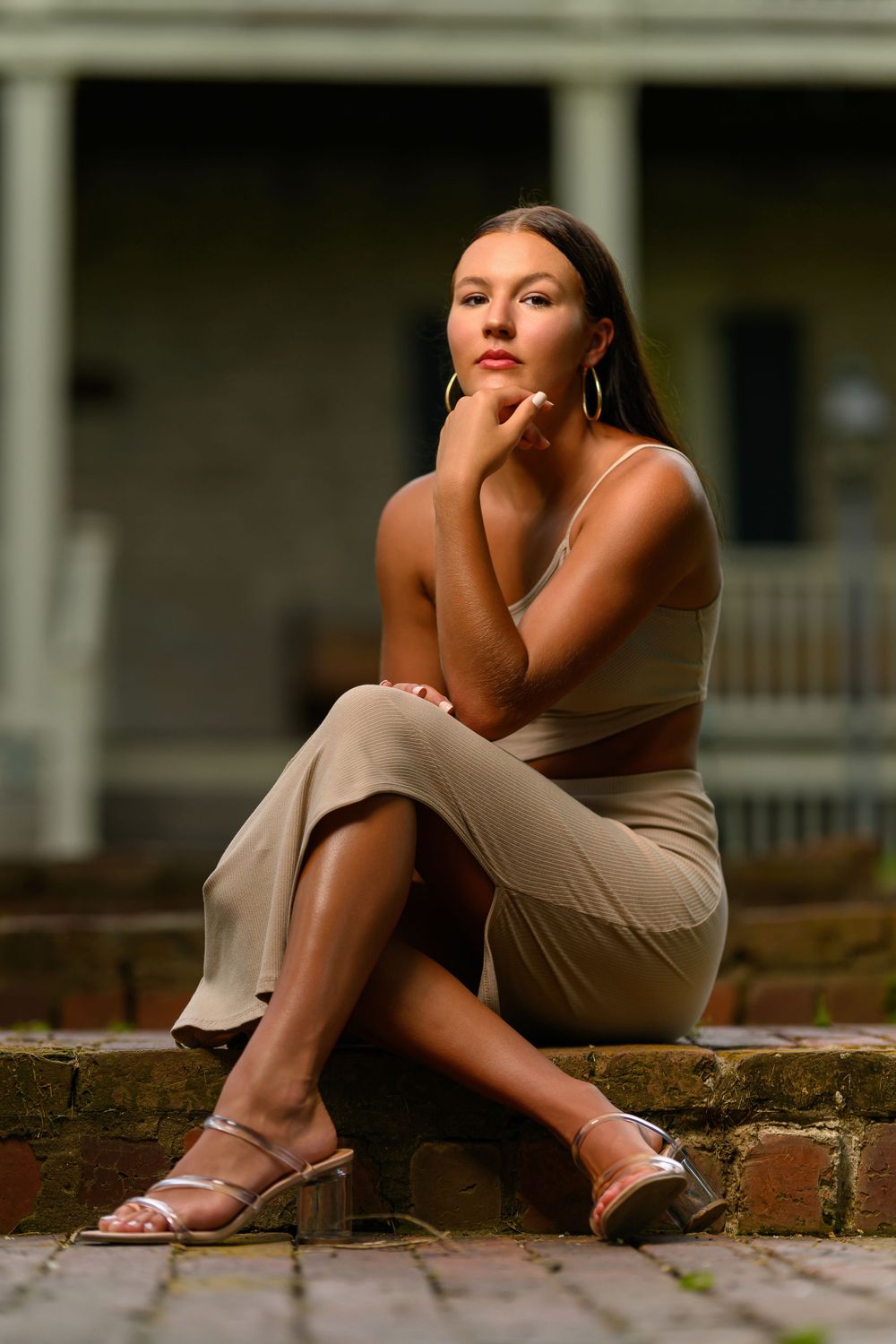 Portrait of model in neutral tones posing on brick steps at sunset.