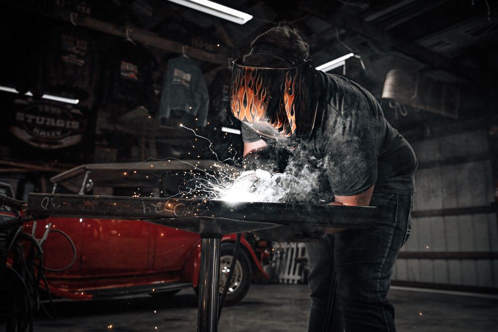 Welder creating sparks while working on metal in dark industrial workshop.