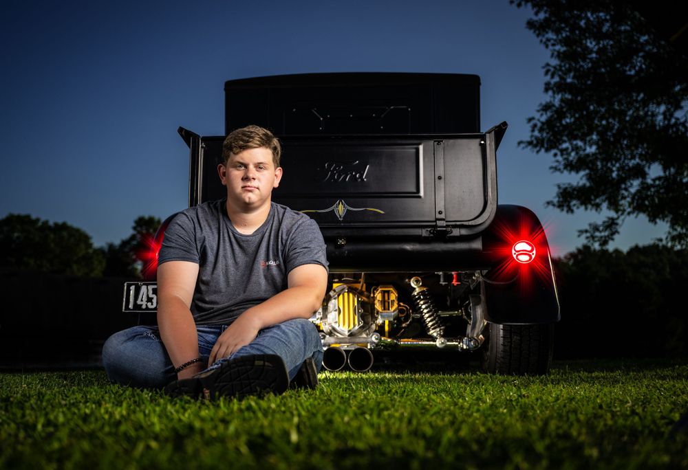 Portrait of mechanic sitting in front of truck tailgate at dusk.