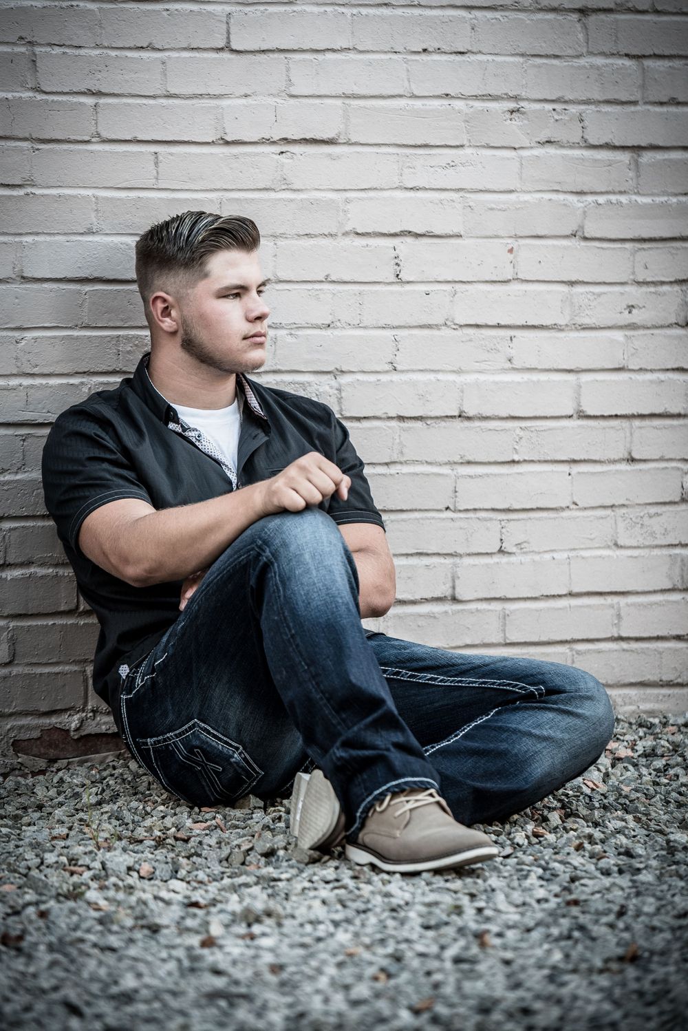 Senior guy sitting against brick wall