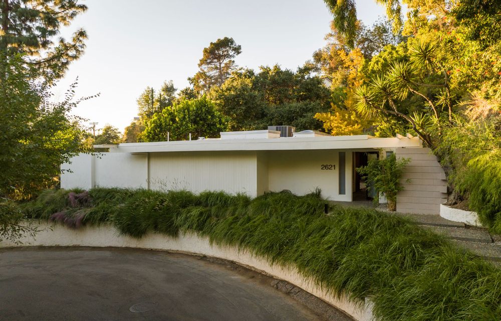 Mid-century modern home exterior with curved driveway and landscaped garden.