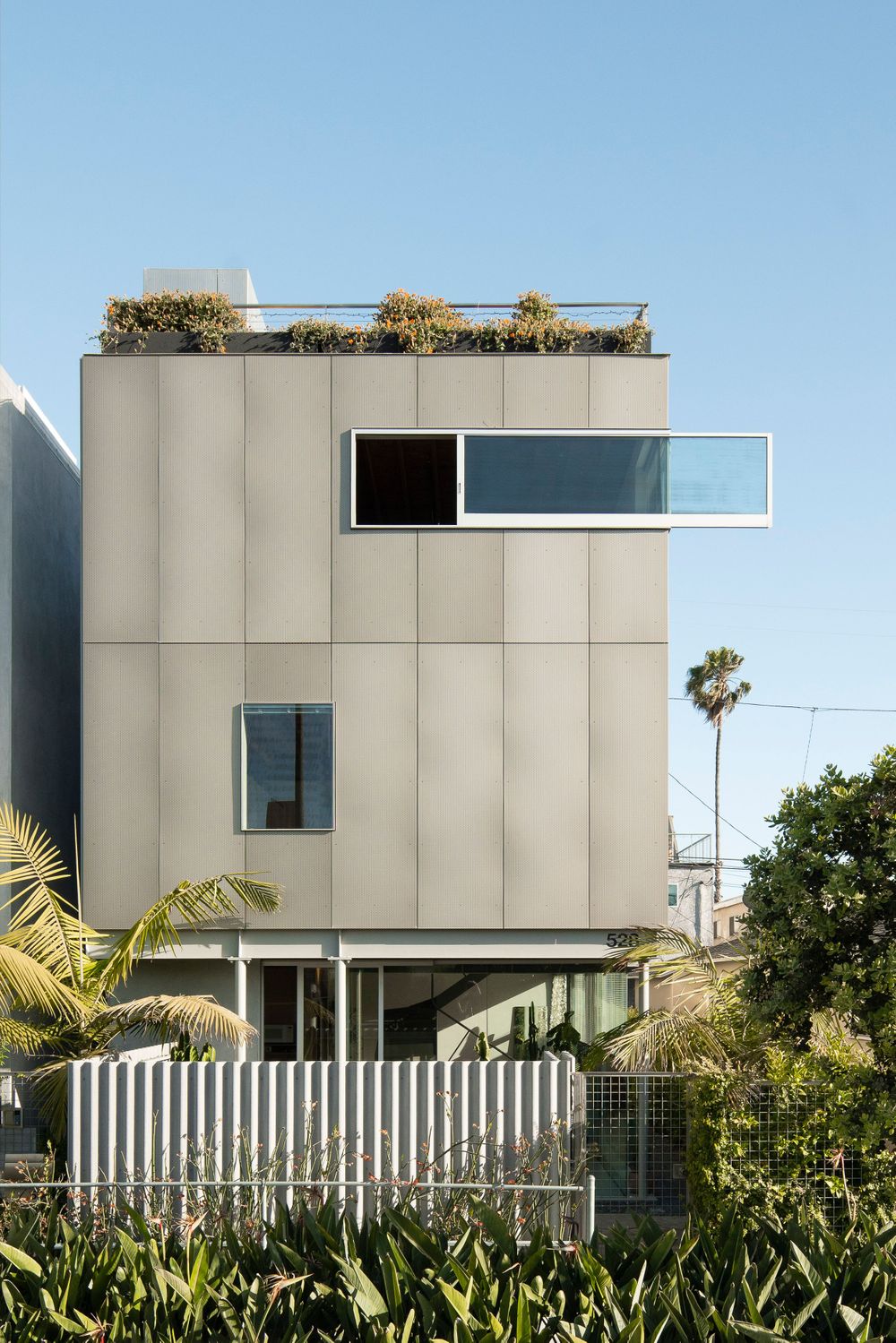 Contemporary white cubic house with rooftop garden and horizontal window detail.