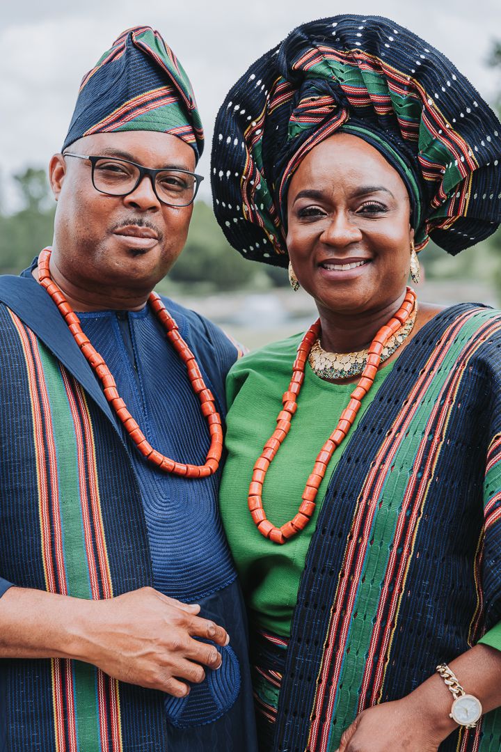 Couple wearing traditional African attire with beaded necklaces and headwraps in outdoor photoshoot.