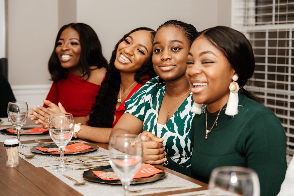 A group of friends enjoying a meal together at a dining table with wine glasses and place settings.