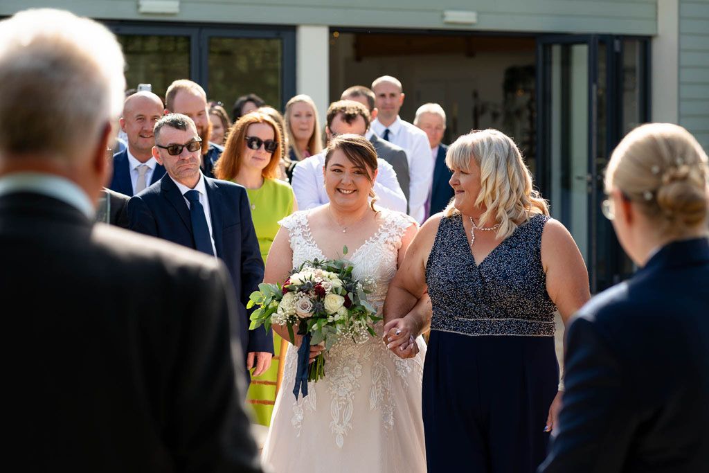 LGBTQ Bride walking down isle at Harefield Barn, Devon Wedding