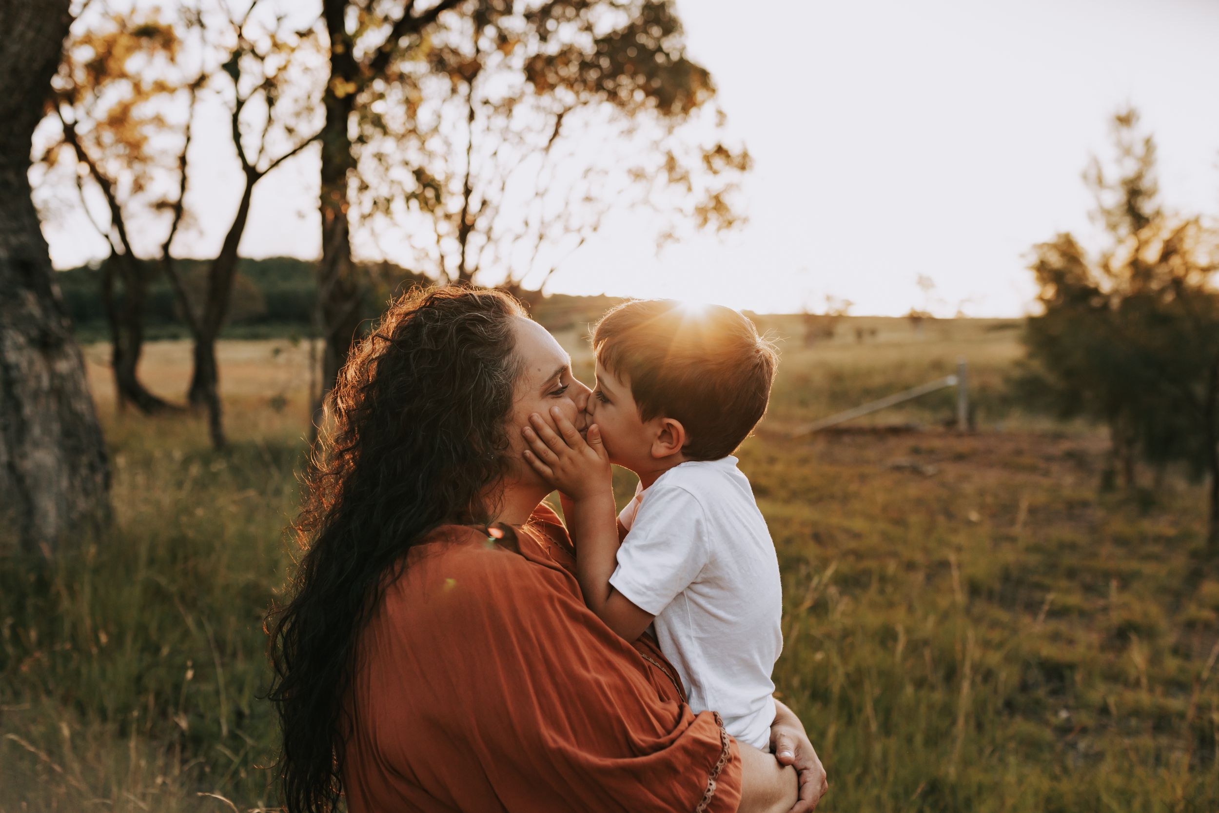 Canberra family photographer. National Arboretum.  Photo of mother and child kissing, sunset, earth tone edit.