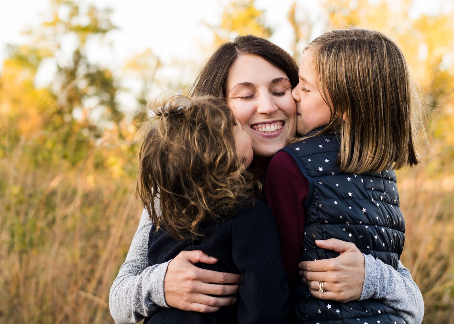 In this picture, mom is being hugged by her daughters.