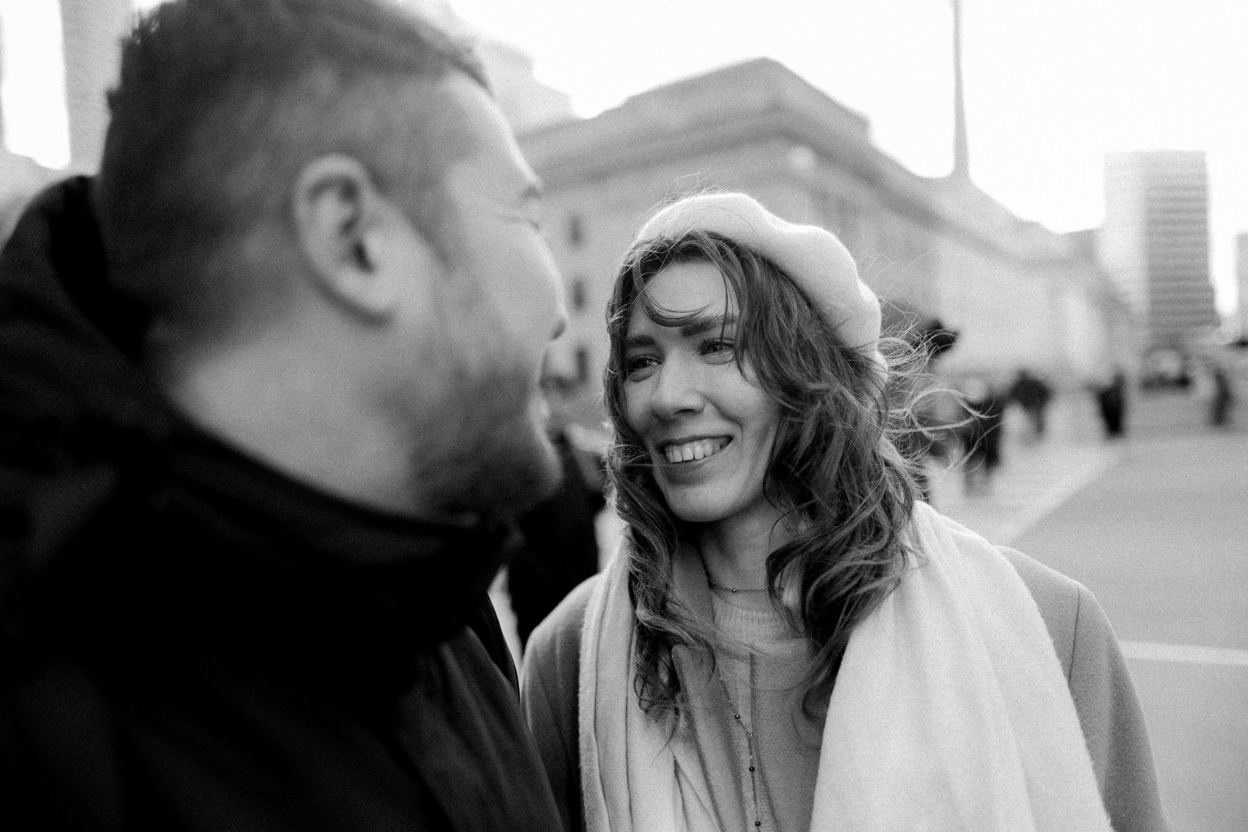 A candid black and white street photo showing two people sharing a joyful moment in the city.