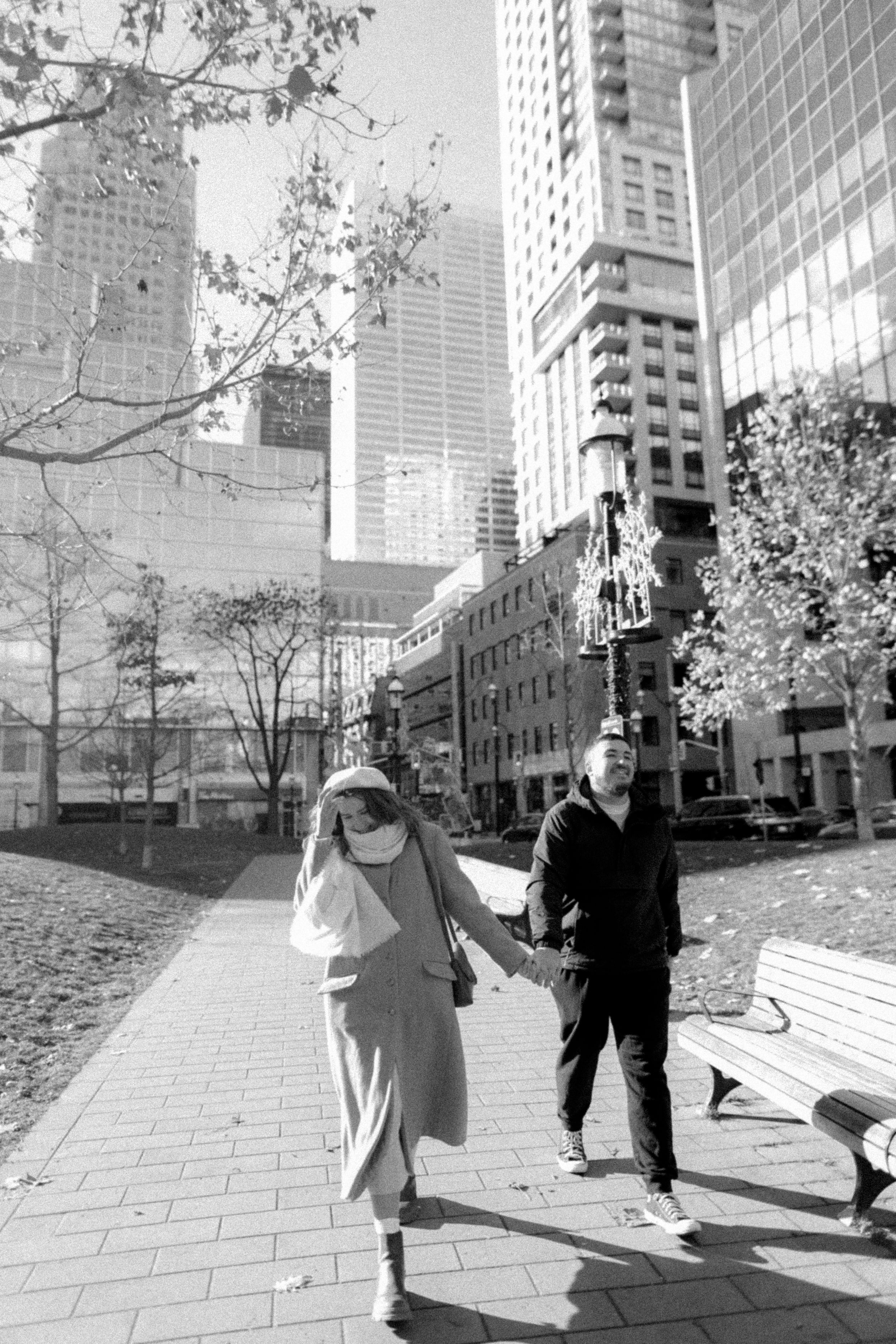 A couple walking together on a path with modern buildings in black and white photography.