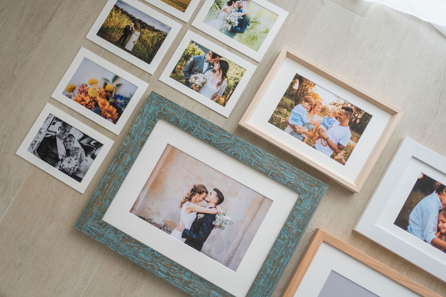 Assorted framed wedding and family photos arranged on light wooden floor.