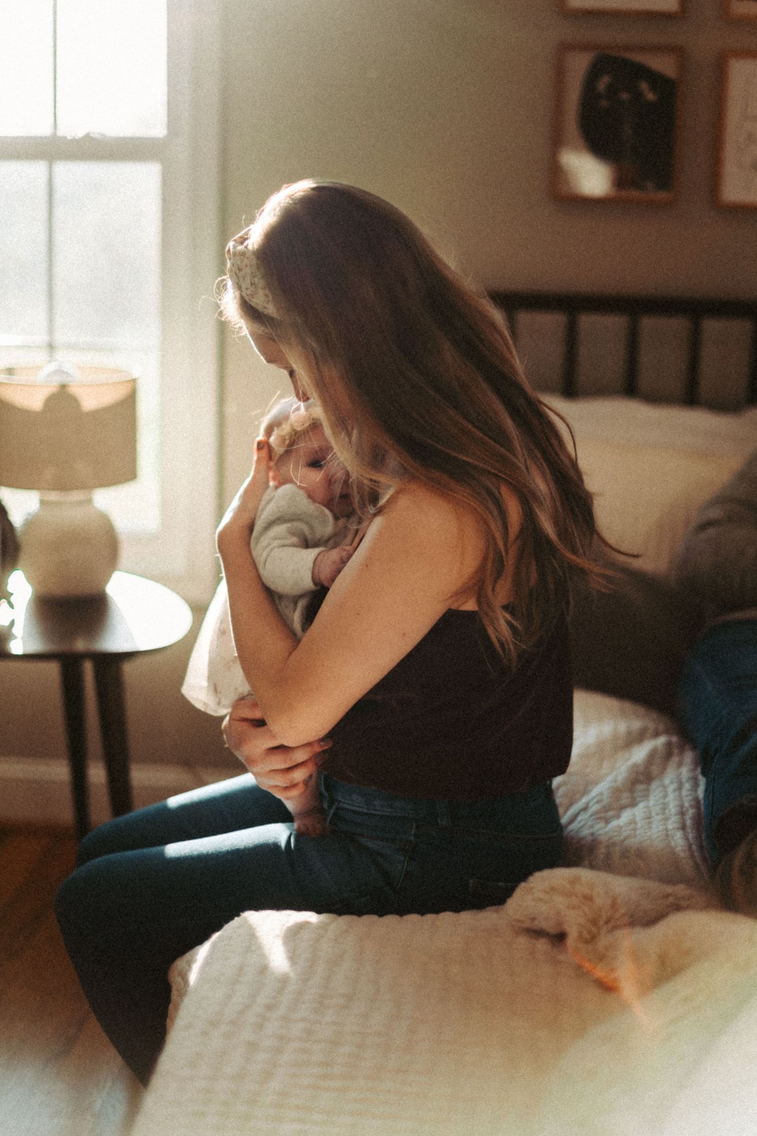 Tender moment in sunlit bedroom with soft window light filtering through.