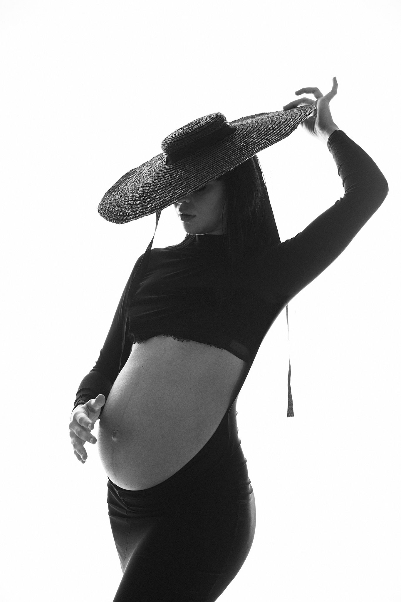 High contrast maternity silhouette with wide hat and crop top in black and white.