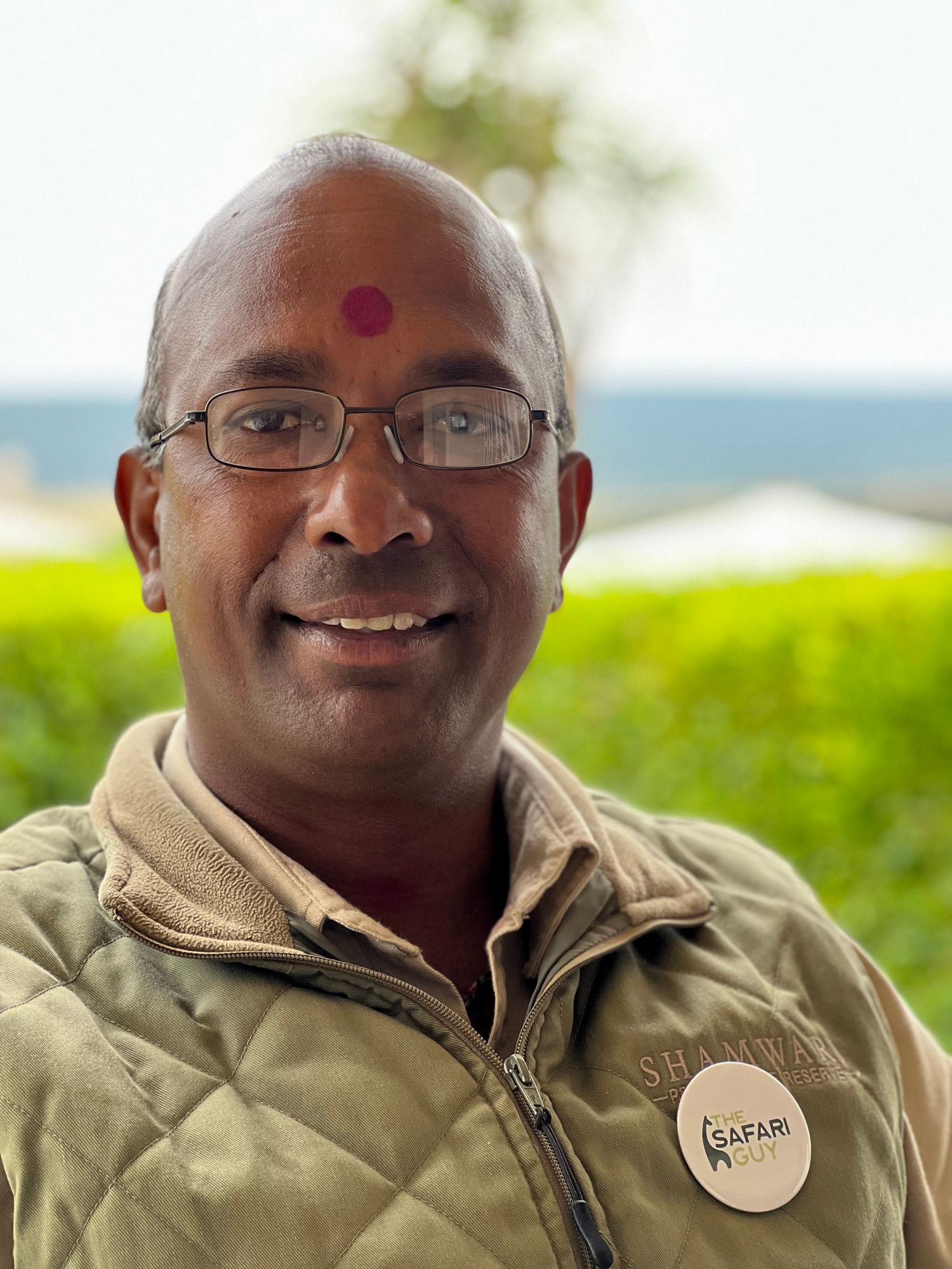 Guide in safari uniform sharing warm smile at wildlife reserve.