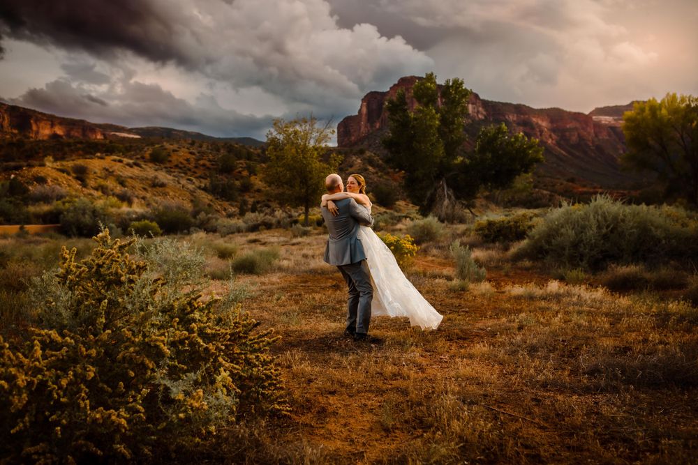 A wedding couple dance together outside in Colorado mountains with a dramatic sky behind them