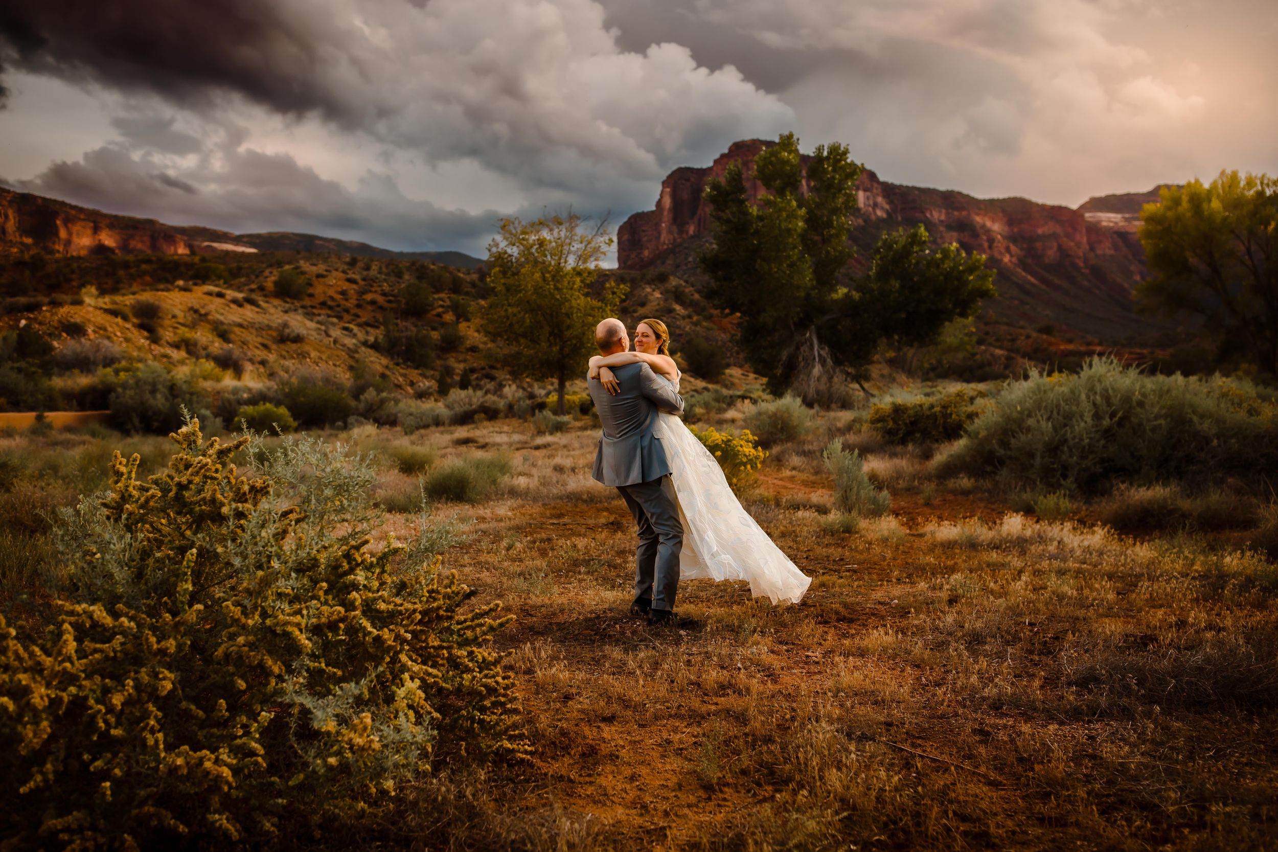 A wedding couple dance together outside in Colorado mountains with a dramatic sky behind them