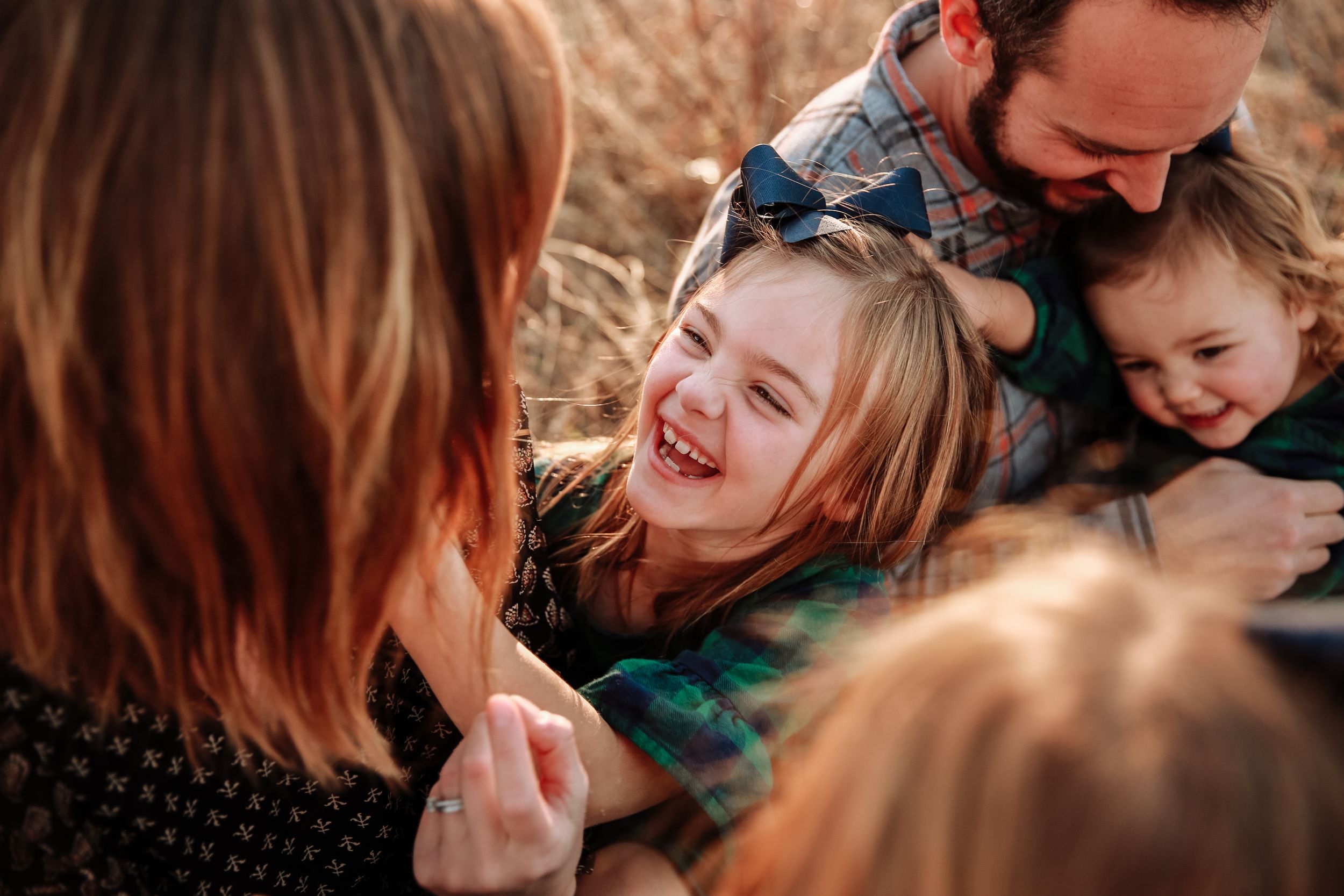 Family of five candidly laughing in a field