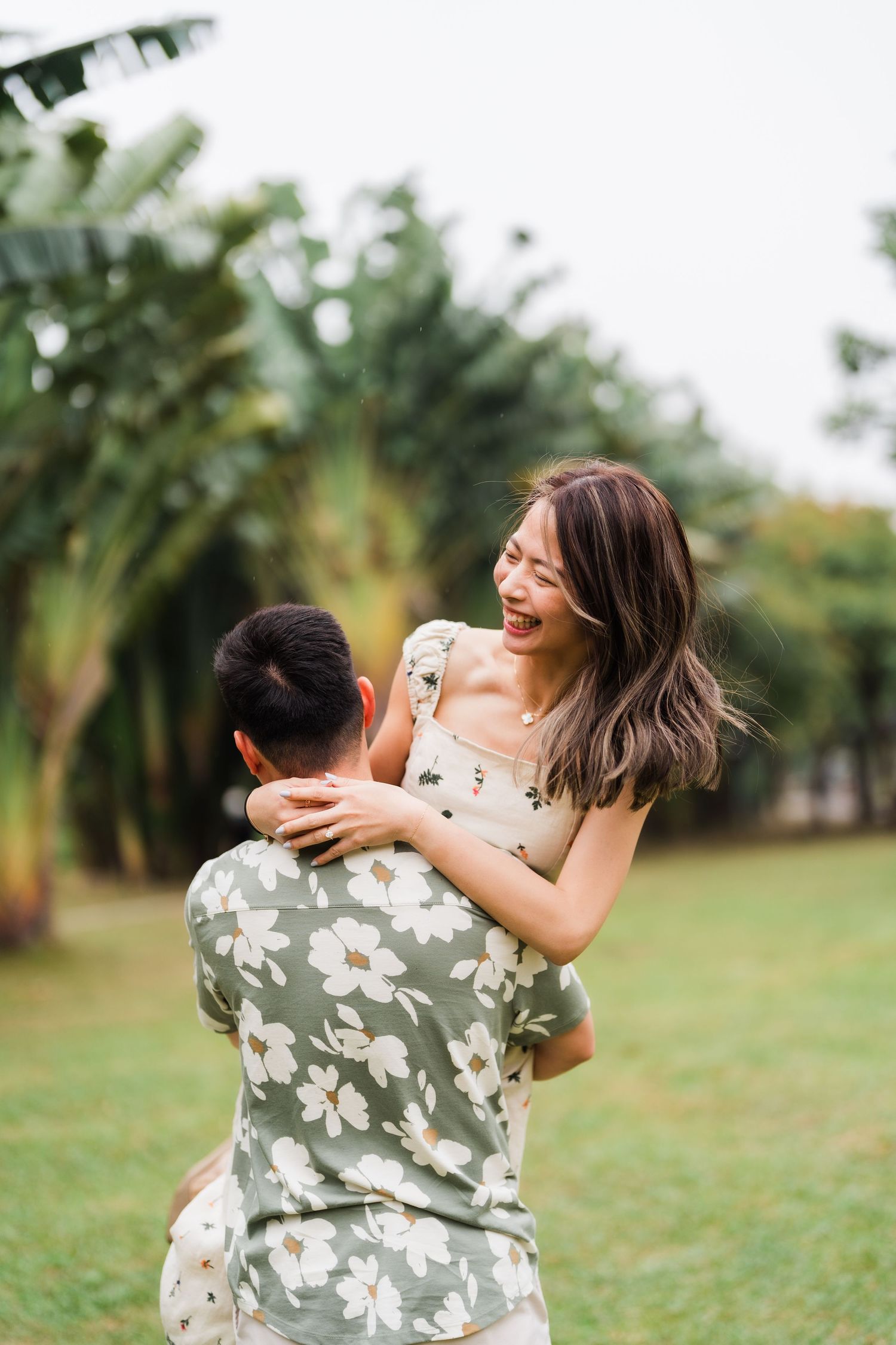 A couple sharing a playful moment in a tropical garden setting.