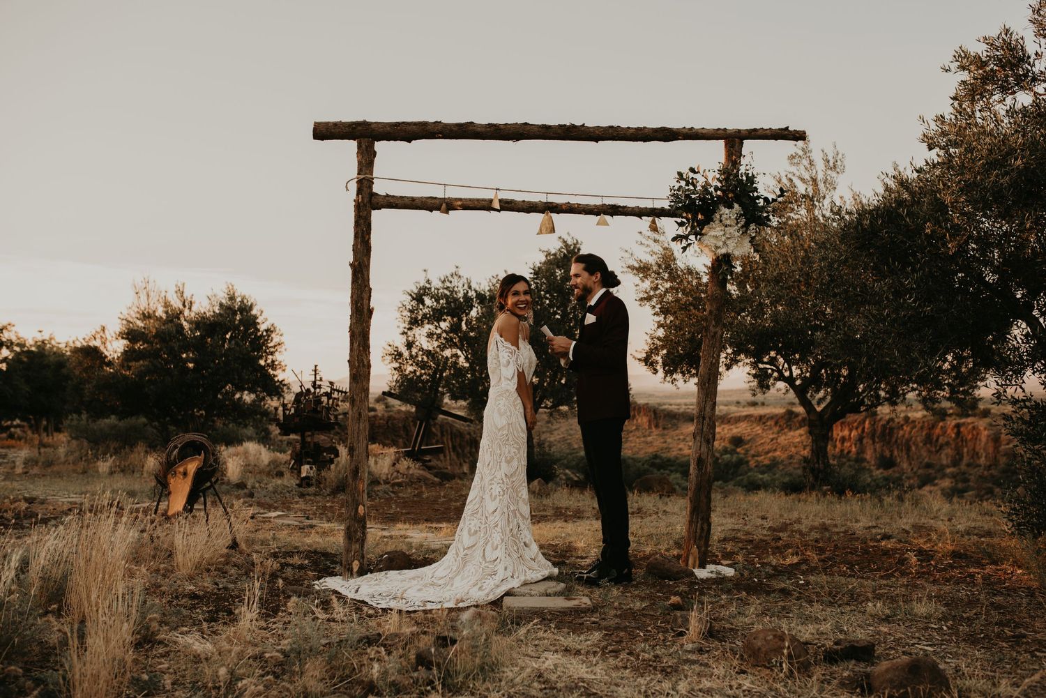 Desert wedding ceremony setup with wooden arch and mountain backdrop.