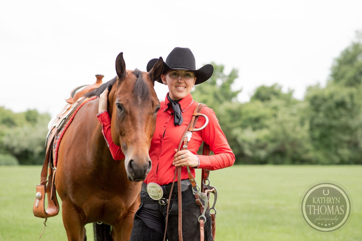 Brown horse with western tack alongside handler in red shirt and black cowboy hat.