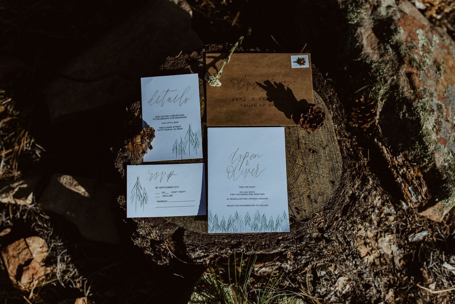 Elegant wedding invitation suite with white cards and rustic brown envelopes displayed on natural wood texture.