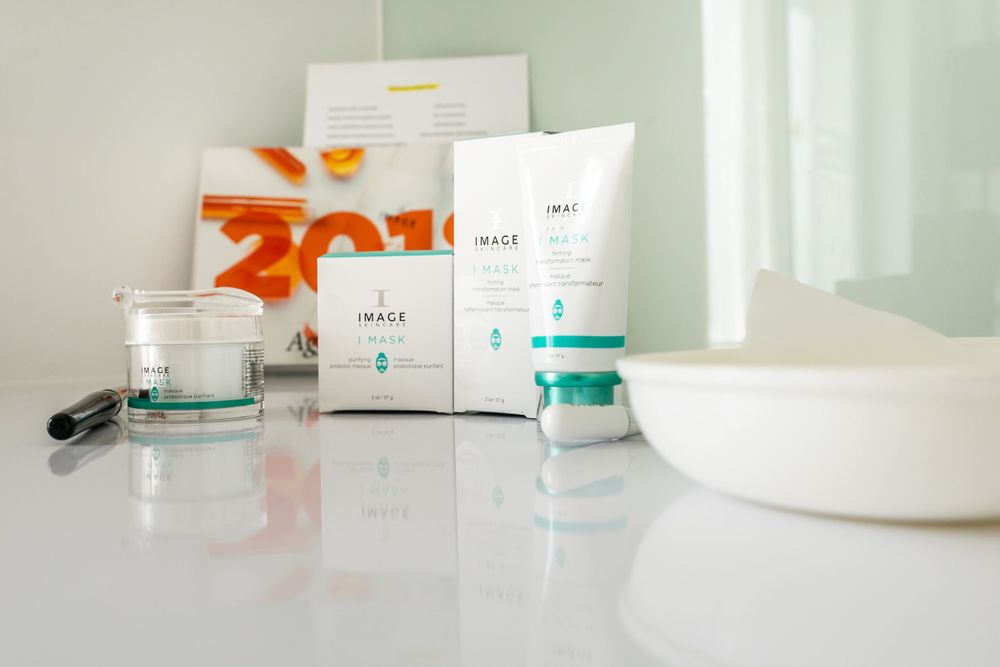 White skincare products and packaging displayed on clean surface with soft lighting.