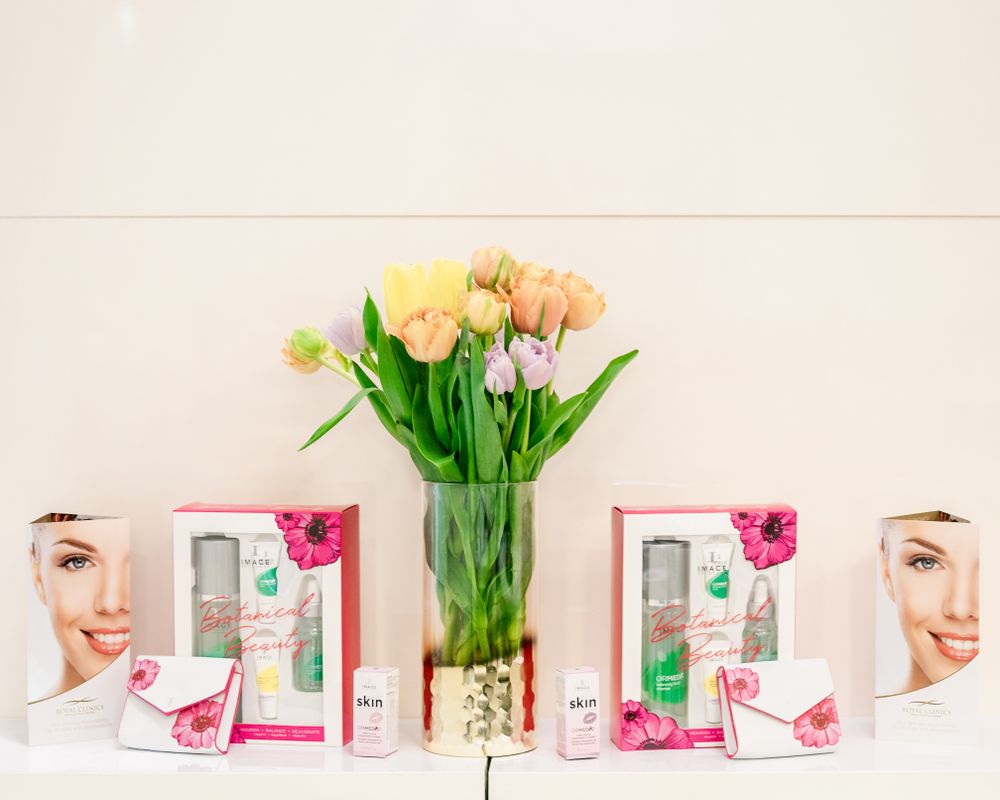 Display of skincare products with pink packaging alongside fresh tulips on white surface.