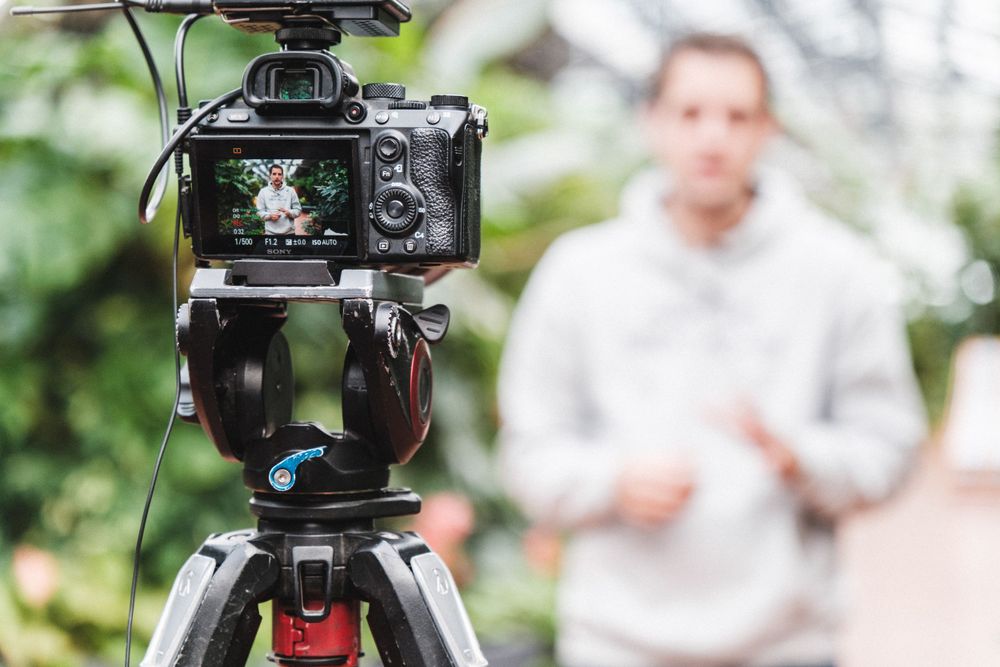 Professional camera setup on tripod filming outdoor video content.