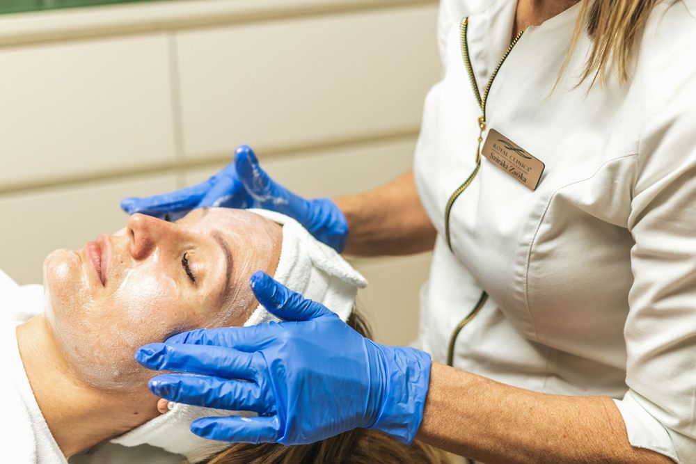 Professional spa therapist performing facial treatment with blue gloves.