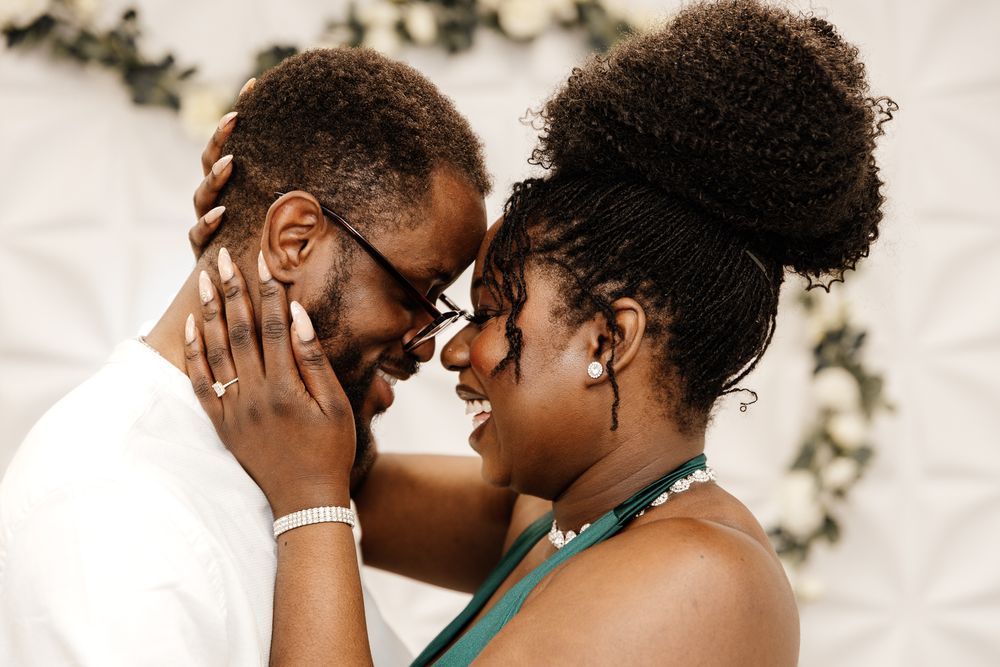 Two people share an intimate moment with their faces close together, showing affection and joy.