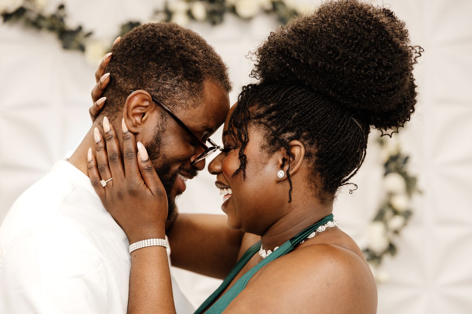 Two people share an intimate moment with their faces close together, showing affection and joy.
