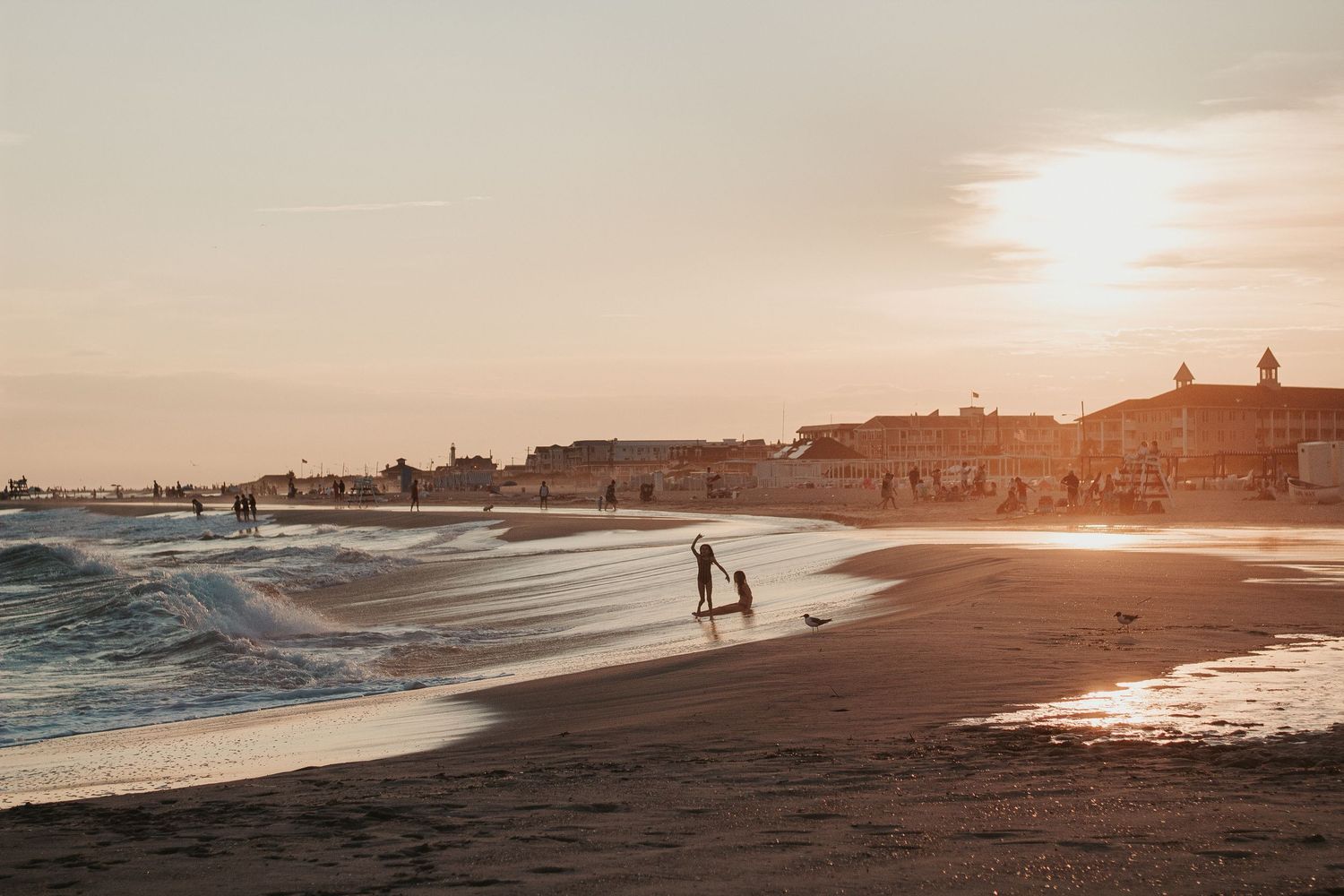 Golden sunset over a beach with silhouetted figures walking along the shoreline.