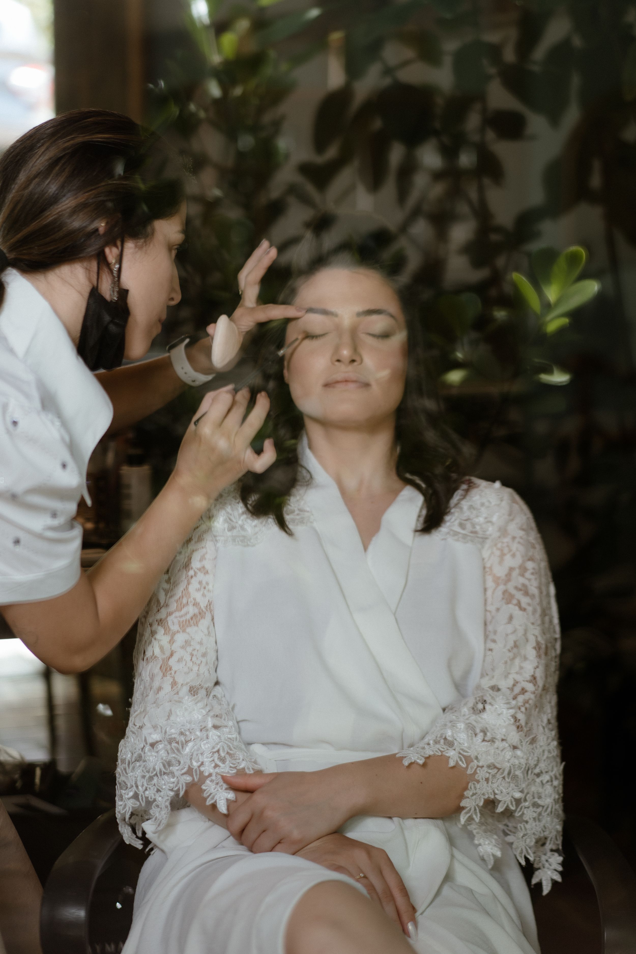 Wedding day preparation showing makeup application in a serene indoor setting.