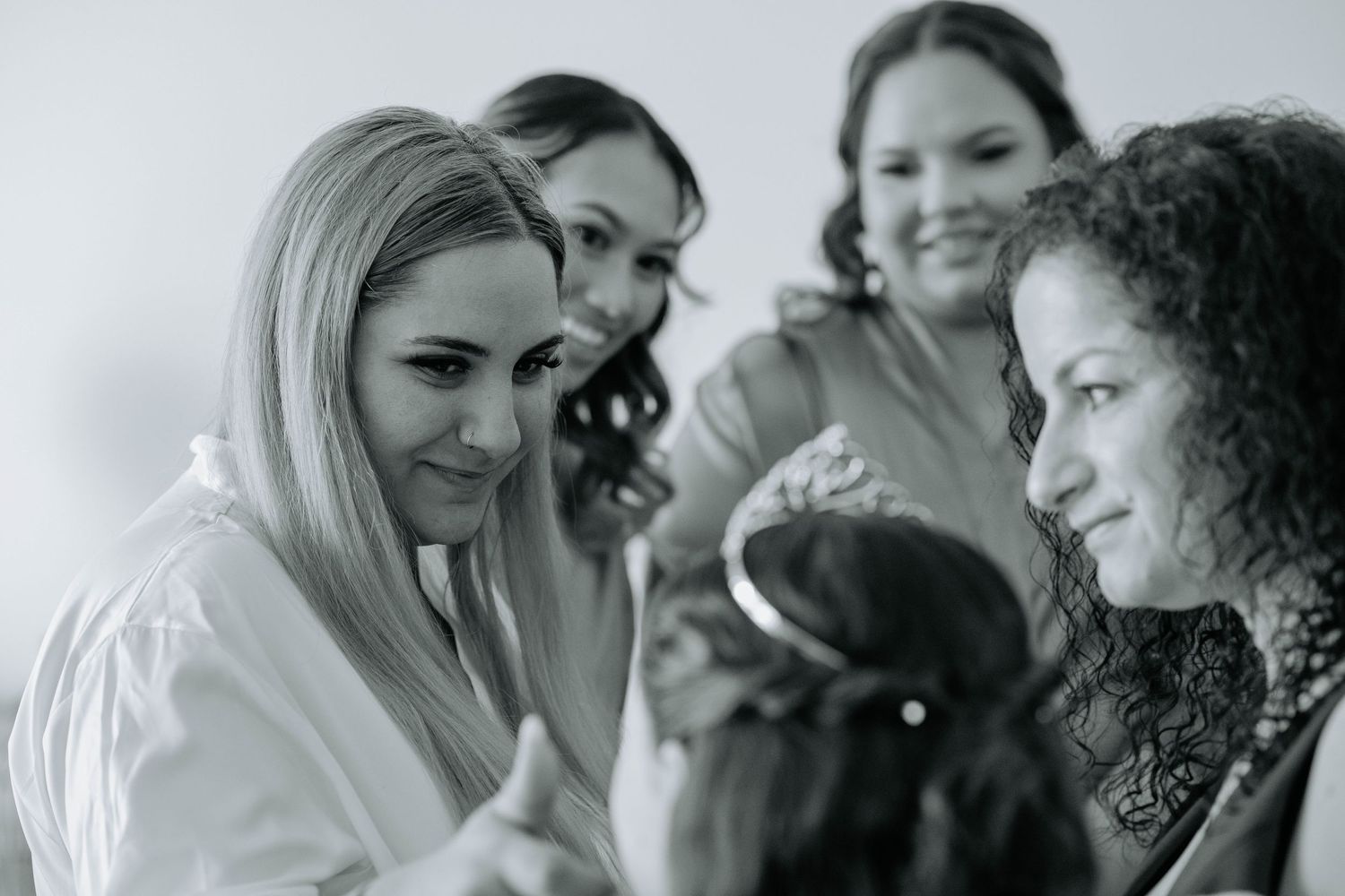 Black and white photo of bridal party sharing joyful moment during wedding preparations.