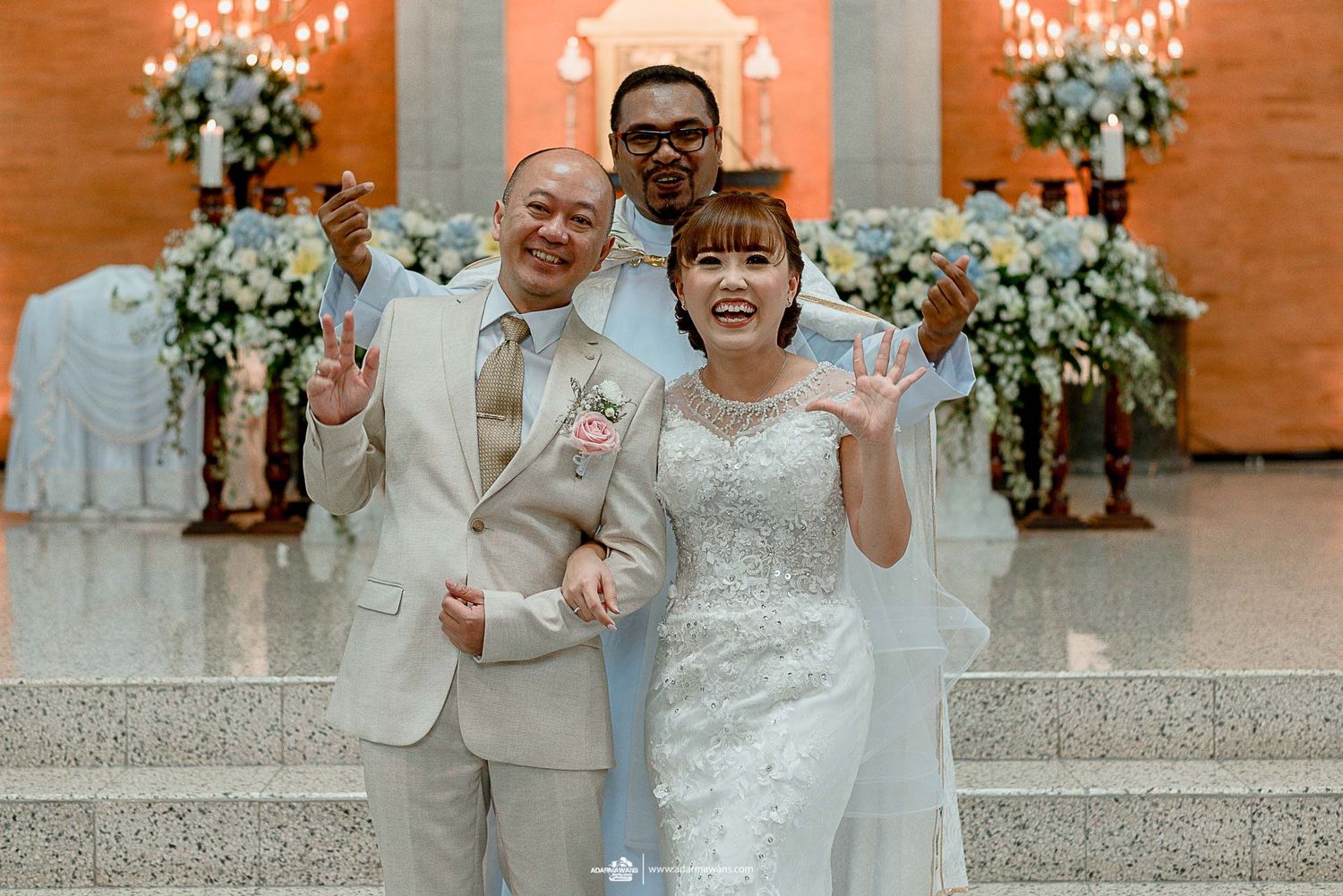 Wedding celebration photo with orange backdrop and decorative white flowers.