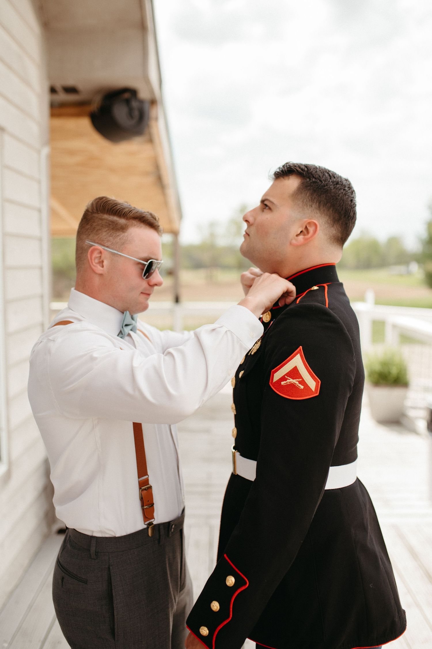 Final adjustments being made to military dress uniform on porch.