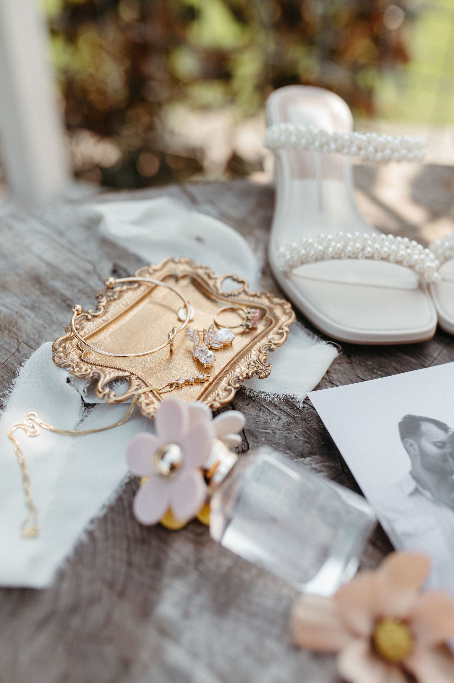 Wedding details featuring ornate gold tray, white sandals, and soft pink flowers.
