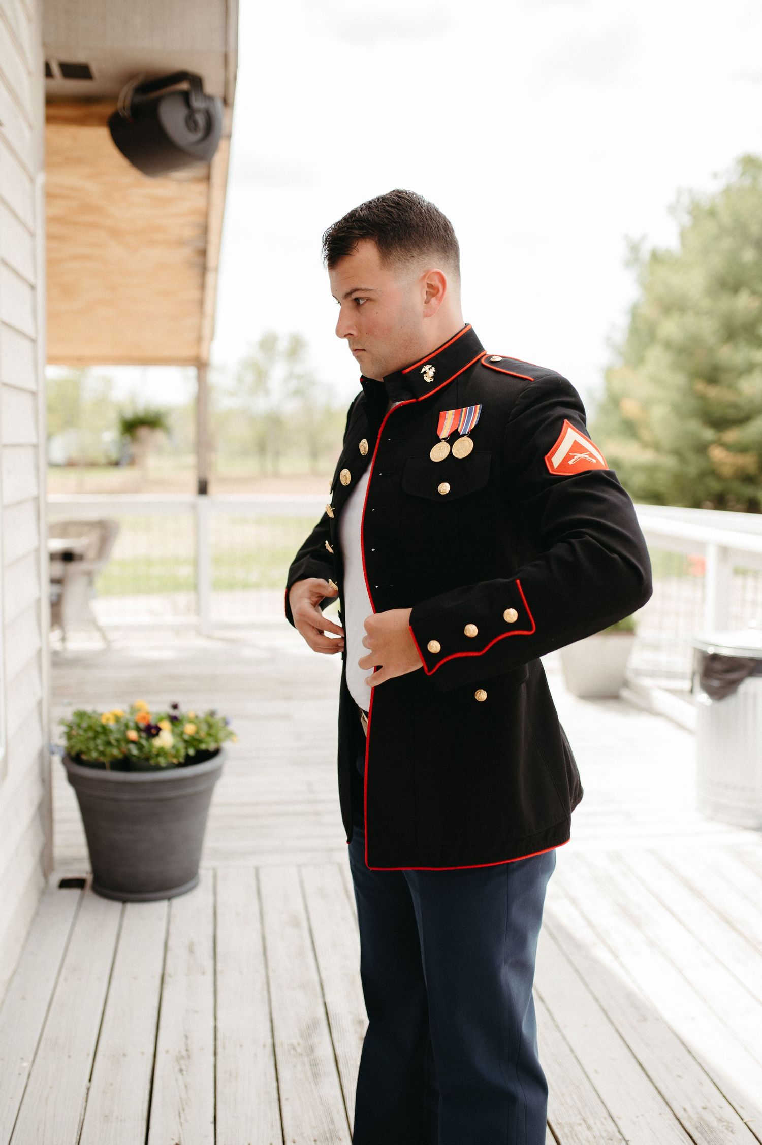 Marine Corps dress uniform being worn on wooden porch with potted plants.