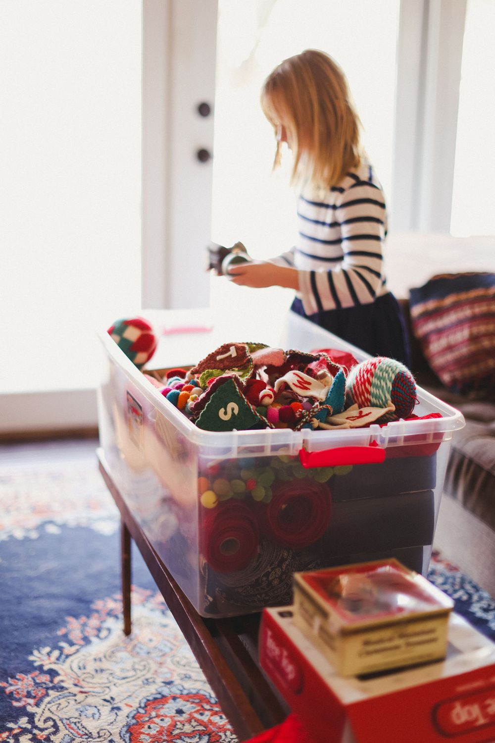 Storage containers filled with holiday decorations sit on a patterned rug.