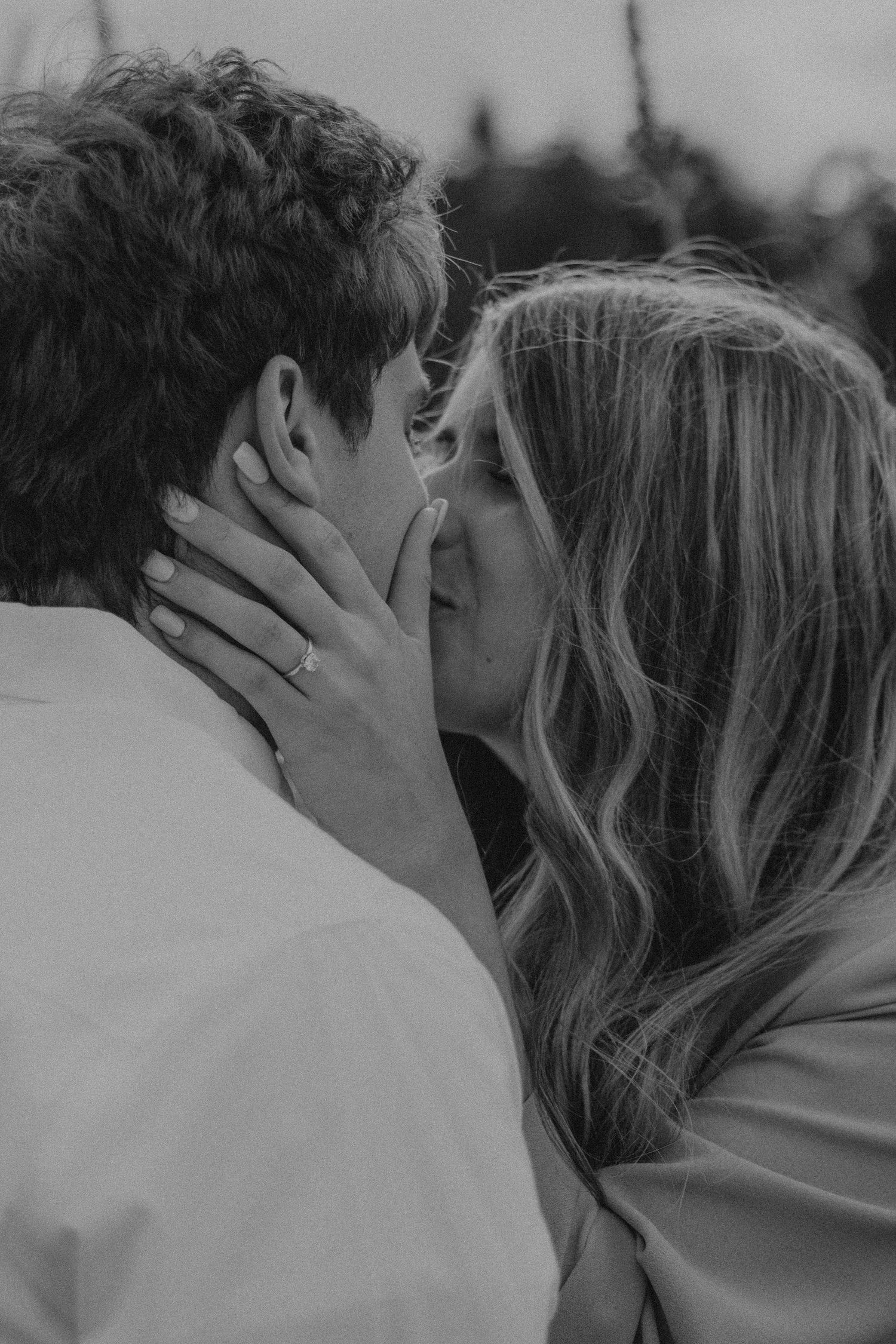 Black and white romantic close-up of a tender kiss between a couple in an intimate moment.