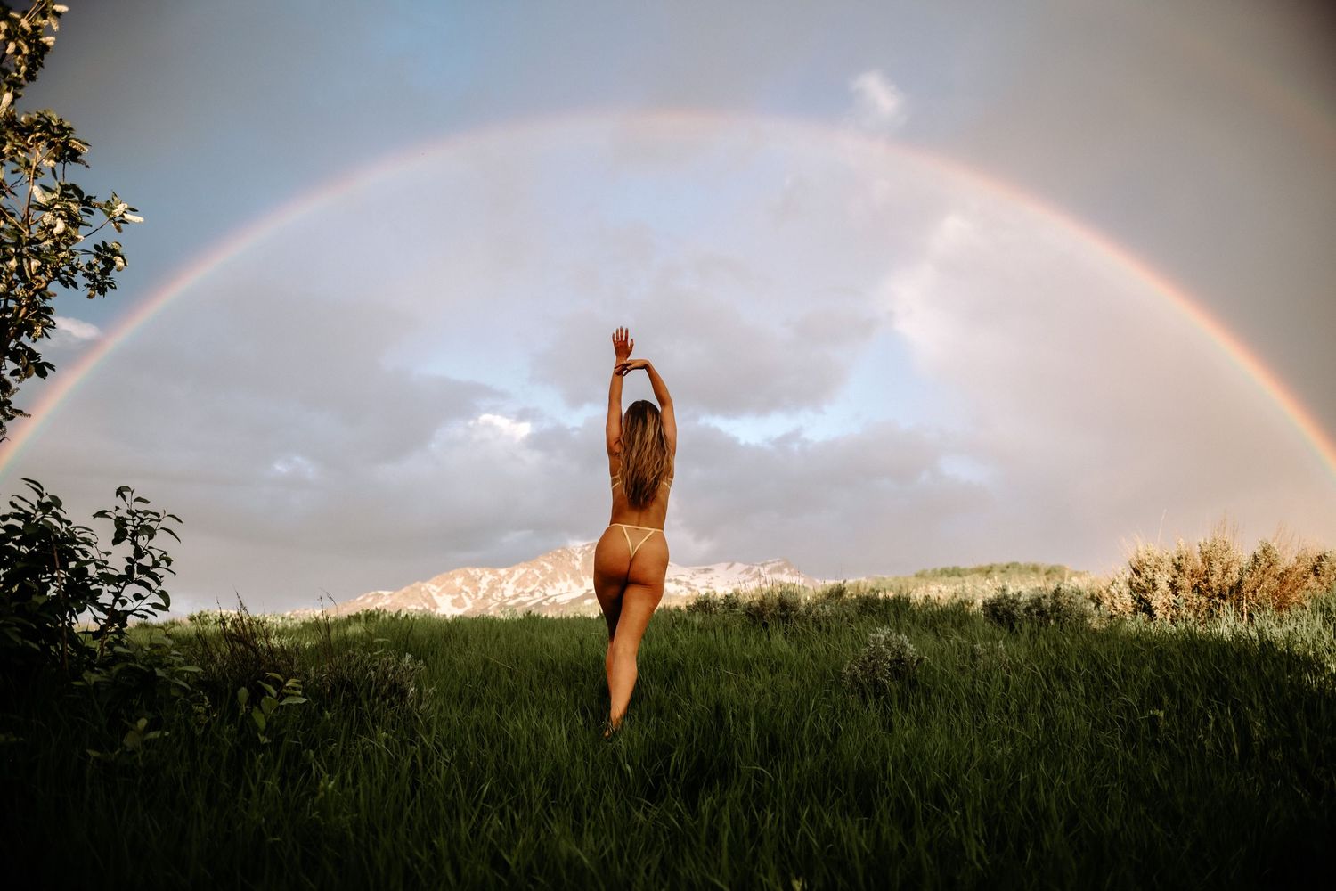 Woman walking away under a rainbow in lingerie for outdoor boudoir photoshoot.