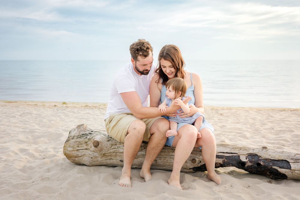 A relaxed family moment on a beach log by the ocean shore.