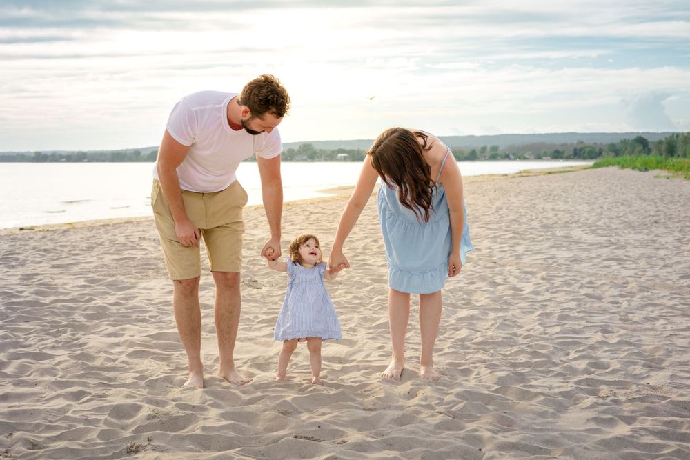 Family holding hands while walking together on sandy beach.