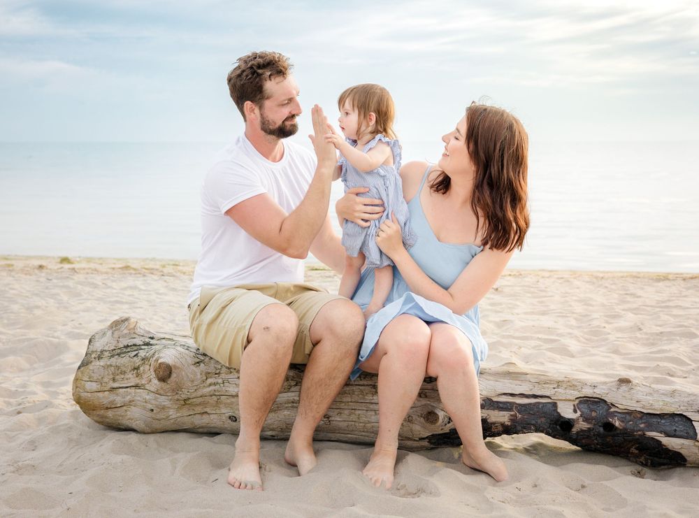 A joyful family scene captured on driftwood at the beach during golden hour.