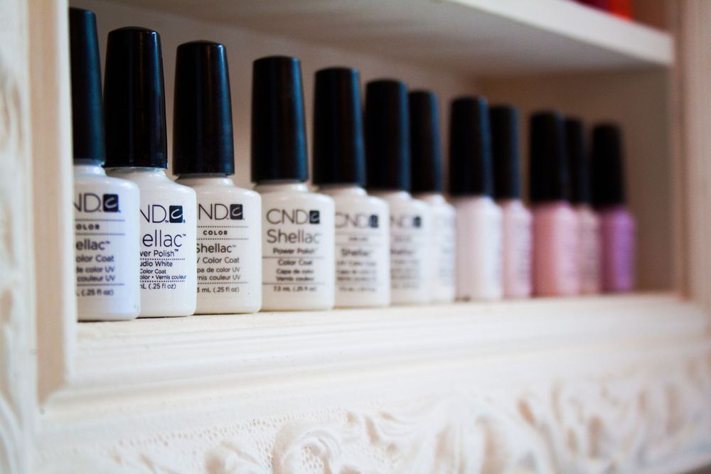 Close-up view of organized nail polish bottles on white shelving.