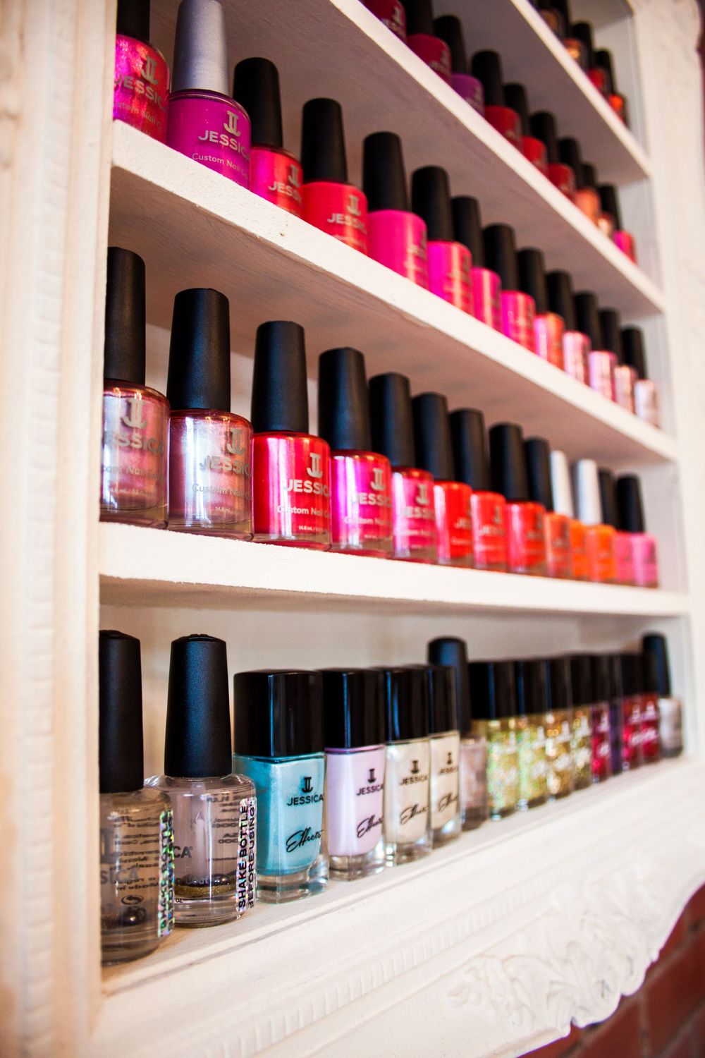 Long shelf display of colorful nail polish bottles arranged in neat rows.