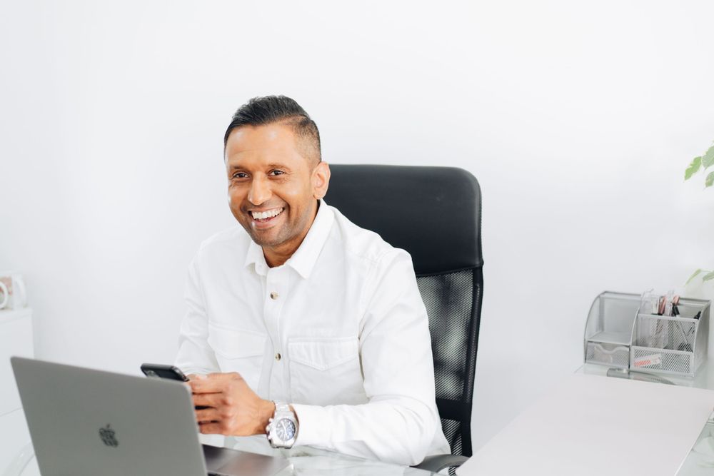 Business professional smiling while working on laptop at modern office desk.