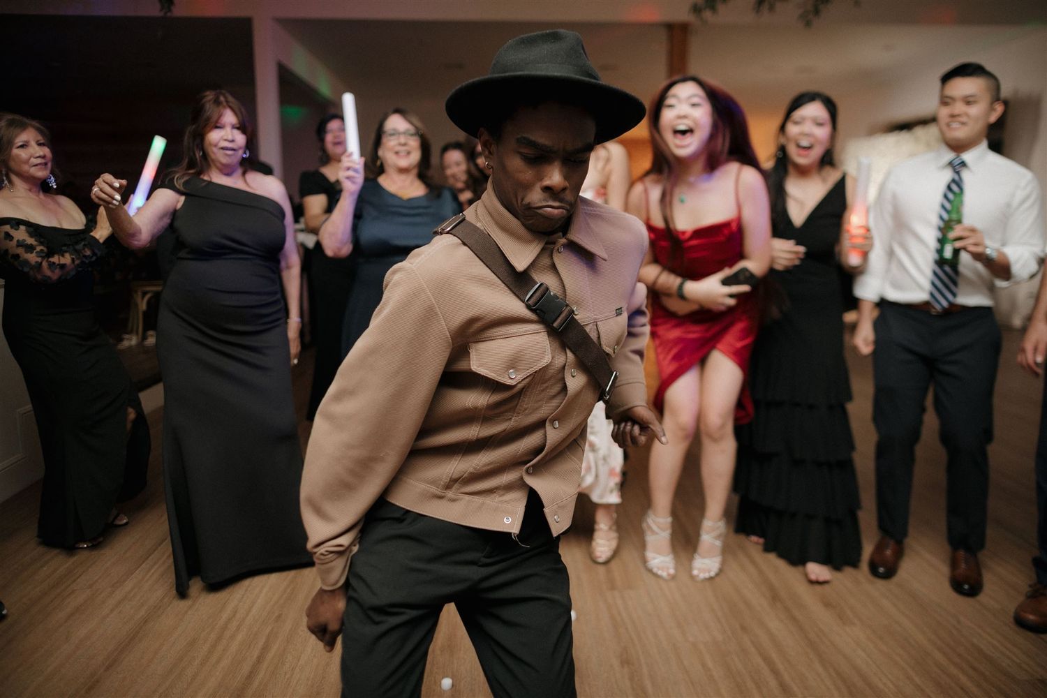 Wedding reception dance floor with guests in formal attire and someone in a western-style outfit.