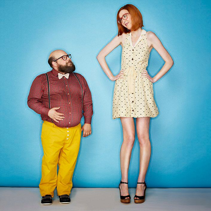 Studio portrait against blue backdrop showing contrasting outfits and heights.
