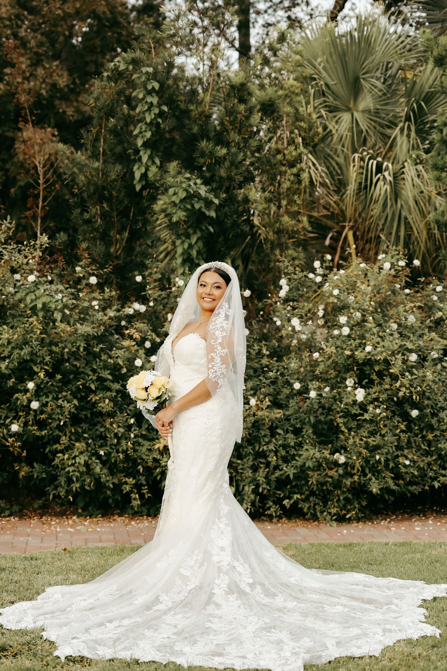 Full-length bridal portrait featuring intricate lace wedding gown with dramatic cathedral train.